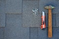 Top view on asphalt bitumen shingles on a roof with hammer,nails and stationery knife background