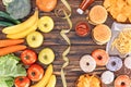 top view of assorted junk food, fresh fruits with vegetables and measuring tape on wooden table Royalty Free Stock Photo