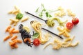 Top view of assorted raw pasta and fresh ingredients near spoon and fork on white background Royalty Free Stock Photo