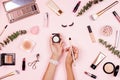 Flat lay of professional Cosmetics set on pastel pink background. Woman holding hands makeup brush Royalty Free Stock Photo