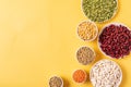 Top view of assortment of peas, lentils, beans and legumes over yellow background