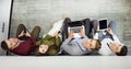 Top view of attractive girls and guy using a laptop, looking at camera and smiling while sitting on the floor. Royalty Free Stock Photo