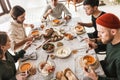 Top view of attractive international friends sitting at the table full of food eating together. Young colleagues having