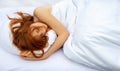 Top view of attractive, young, red-haired woman relaxing in bed hugging a soft white pillow, sleeping Royalty Free Stock Photo