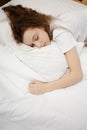 Top view of attractive young woman sleeping in bed hugging soft white pillow. Teenage girl resting, good night sleep Royalty Free Stock Photo