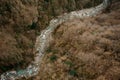 Top view of azure forest river flowing among rocks and yellow trees in Martvili canyon