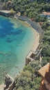 Top view of azure sea, sandy beach with people along walls of old castle. concept of beach holiday, summer vacation Royalty Free Stock Photo