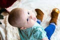 Top view baby in jeans and shoes sits near a Christmas tree, toys balls lie around