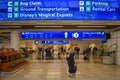 Top view of Bag Claim, Ticketing and Check-in blue signs and woman walking with baggage at Orlando International Airport.