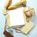 Top view bakery products such as bread, chocolate, mold and empty white book for text on wood plate.