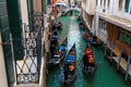 Top view from a balcony over a narrow canal in romantic Venice, with gondoliers steering gondolas through the waterway