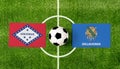 Top view ball with Arkansas vs. Oklahoma flags match on green soccer field