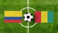 Top view ball with Colombia vs. Guinea flags match on green football field