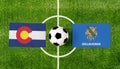 Top view ball with Colorado vs. Oklahoma flags match on green soccer field