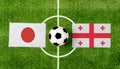 Top view ball with Japan vs. Georgia flags match on green football field