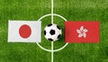 Top view ball with Japan vs. Hong Kong flags match on green football field Royalty Free Stock Photo