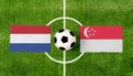 Top view ball with Netherlands vs. Singapore flags match on green football field