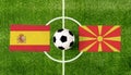 Top view ball with Spain vs. Macedonia flags match on green soccer field