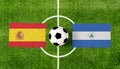 Top view ball with Spain vs. Nicaragua flags match on green soccer field