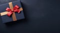 Top view of the banner with a blue gift box with a gold satin ribbon and a red bow on a dark background Royalty Free Stock Photo