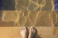 Top view of bare female foot standing beside the edge of swimming pool with wave on the sunny day over the stairs Royalty Free Stock Photo