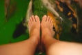 Top view. bare foot of young women has carp fishes in water are