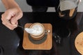 Top view hand of barista man pouring the milk foam into a cup of coffee. carefully