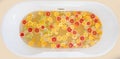 Top view of bathtub filling with water, mixed slices of fresh citrus fruits.