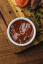 Top view of bbq sauce in bowl and delicious roasted meat with tomato