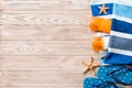 Top view of Beach flat lay accessories. sunscreen bottle with seashells, starfish, towel and flip-flop on wooden board background