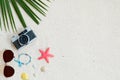 Top view of beach sand with coconut leaves, camera, bracelet made of seashells, sunglasses, shells and starfish. Royalty Free Stock Photo