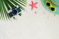 Top view of beach sand with coconut leaves, camera, shells, starfish, sunglasses, shells and straw hat. Royalty Free Stock Photo