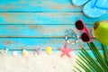 top view of beach sand with slipper, coconut, sunglasses, coconut leaves, starfish, shells, coral and bracelet made of seashells