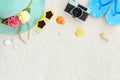 Top view of beach sand with straw hat, sunglasses, shells, camera, slippers and coral. Royalty Free Stock Photo