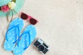 Top view of beach sand with straw hat, sunglasses, slippers and camera.