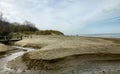 View of a beach washed by sea water, with rocks. Wet sand is drawings rivers and stones under a dramatic cloudy sky Royalty Free Stock Photo