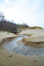 View of a beach washed by sea water, with rocks. Wet sand is drawings rivers and stones under a dramatic cloudy sky Royalty Free Stock Photo