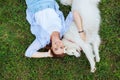 Top view of beaming woman lying near her white dog