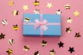 beautiful blue gift box with pink satin ribbon with bow on a pink background with golden stars sequins Royalty Free Stock Photo