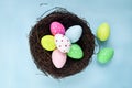 Top view of beautiful colorful Easter eggs in bird nest on blue background, decoration and celebration Easter and spring beginning Royalty Free Stock Photo