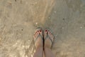 top view on beautiful female feet with red pedicure in slates in the water on the sea sand. the concept of relaxation by Royalty Free Stock Photo