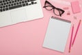 Beautiful flatlay with laptop, glasses and stationery on pink de