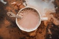 Top view of a beautiful gray mug with warm cocoa and a silver spoon in it, which stands among the mess in the kitchen. A nice