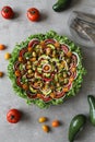 Top view of beautiful Mandala like fresh tomato, avocado, olives, lettuce and onion salad garnished with spring onion & nigella se