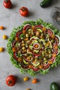 Top view of beautiful Mandala like fresh tomato, avocado, olives, lettuce and onion salad garnished with spring onion & nigella se Royalty Free Stock Photo