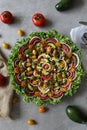 Top view of beautiful Mandala like fresh tomato, avocado, olives, lettuce and onion salad garnished with spring onion & nigella se