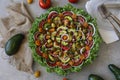 Top view of beautiful Mandala like fresh tomato, avocado, olives, lettuce and onion salad garnished with spring onion & nigella se