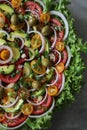 Top view of beautiful Mandala like fresh tomato, avocado, olives, lettuce and onion salad garnished with spring onion & nigella se Royalty Free Stock Photo