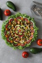 Top view of beautiful Mandala like fresh tomato, avocado, olives, lettuce and onion salad garnished with spring onion & nigella se