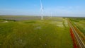 Top view of beautiful railway on background of green field. Shot. Wind farm near beautiful railway in green field